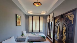 A hotel room with two beds, a large window, a decorative door, and a ceiling light.