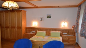 A wooden bedroom with a bed, two nightstands, a chandelier, and a large wardrobe. - FERIENHAUS-TOELDERERHOF (Strassen)