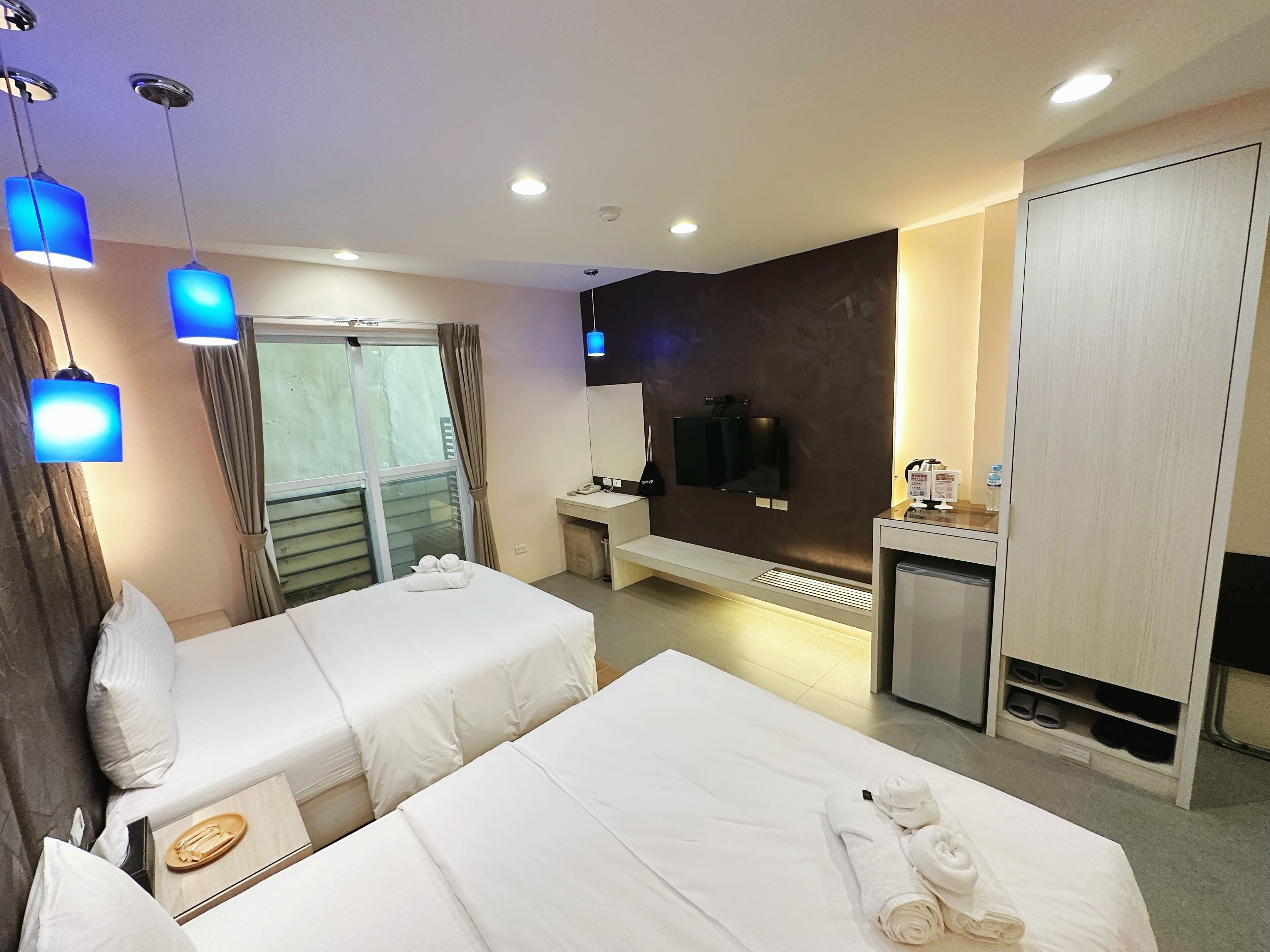Una habitación de hotel con dos camas, un escritorio, un televisor y un minibar.