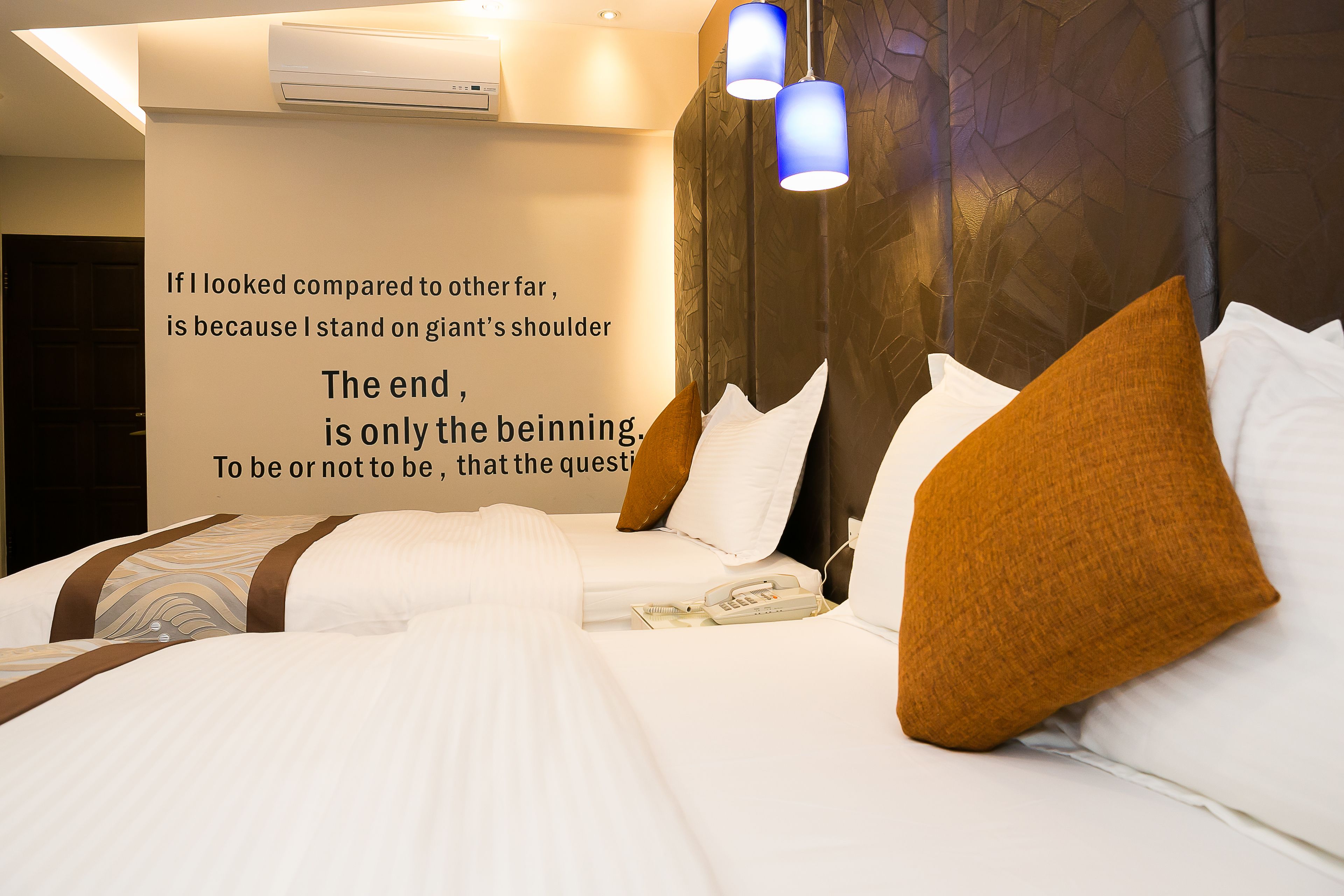 Een hotelkamer met een groot bed, een bedtelefoon en een motiverende quote op de muur.