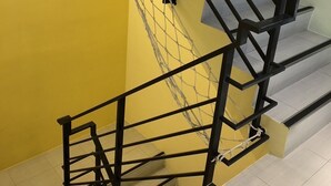 A staircase with black railings and a yellow wall. - Bai Sha Tan Cottage (Hengchun)