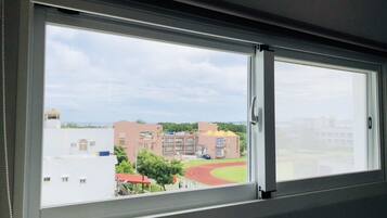 Una ventana con vista a un campo deportivo y edificios.