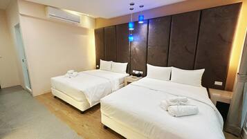 A hotel room with two beds, a wooden floor, an air conditioning unit, and a nightstand with a lamp.