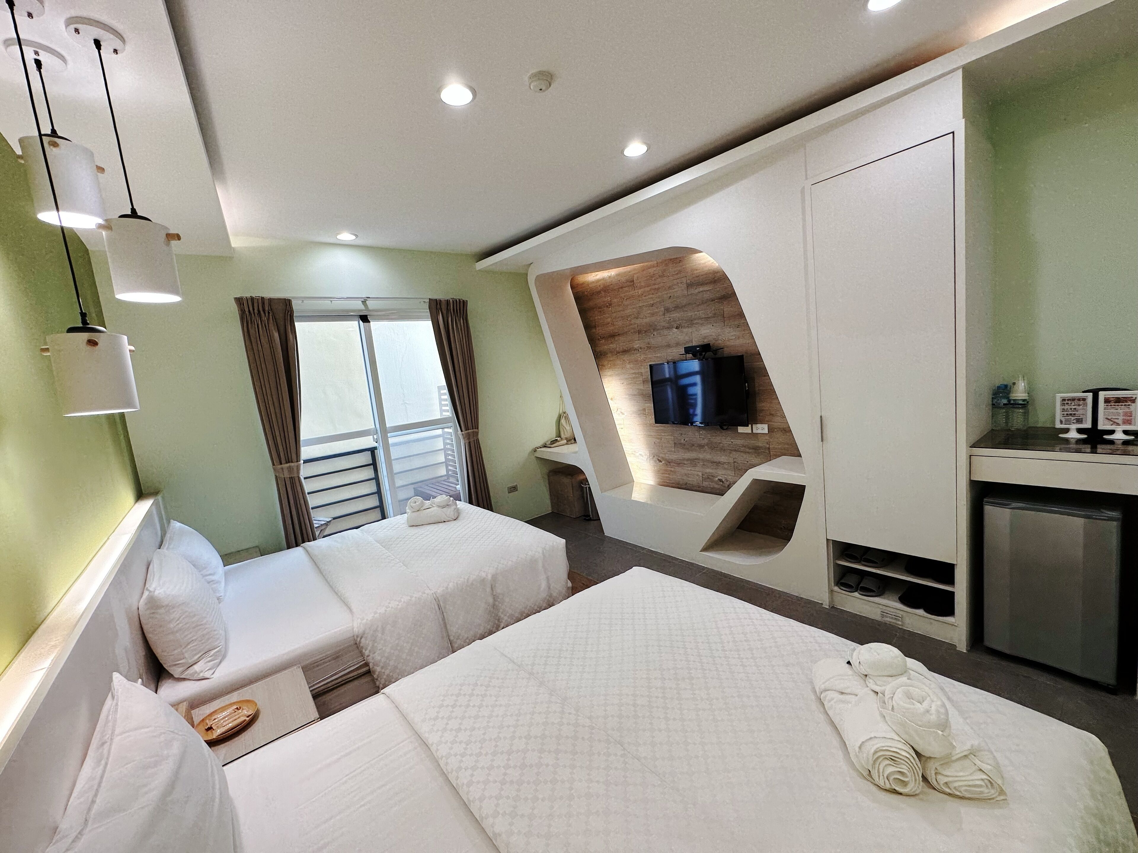 A hotel room with two beds, a TV, a desk, and a minibar.