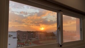 A view through a window of a sunset over a cityscape with buildings and a track. - Bai Sha Tan Cottage (Hengchun)