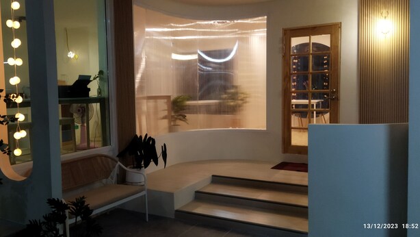 Un interior moderno con una escalera curva, un banco y una ventana con cortinas.