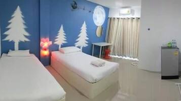 A hotel room with two beds, a small table, a TV, and a window with curtains.