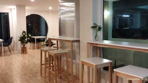 Un interior moderno con una zona de comedor, mesas y sillas de madera.