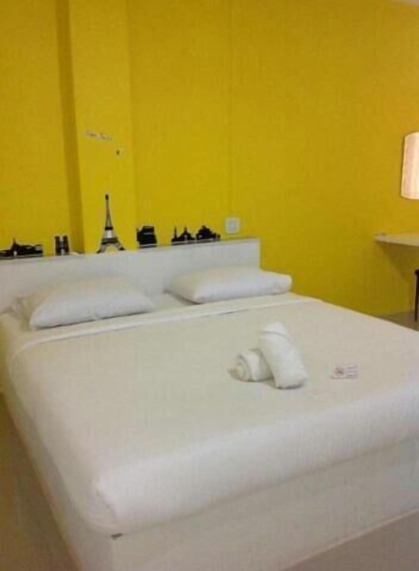 Habitación de hotel con cama, almohadas y cabecera con diseño de paisaje urbano.