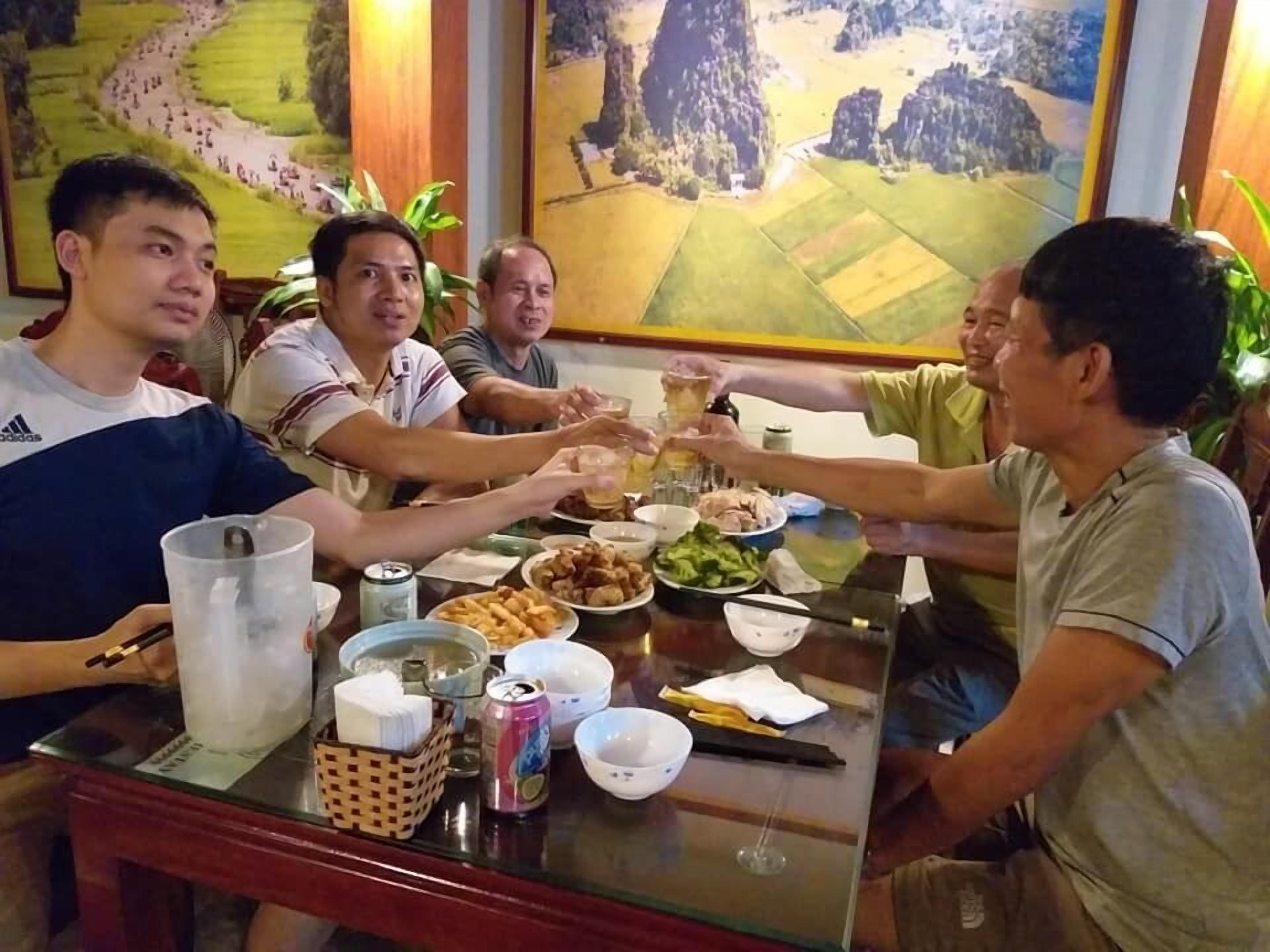 A group of people toasting at a table with various dishes and drinks.