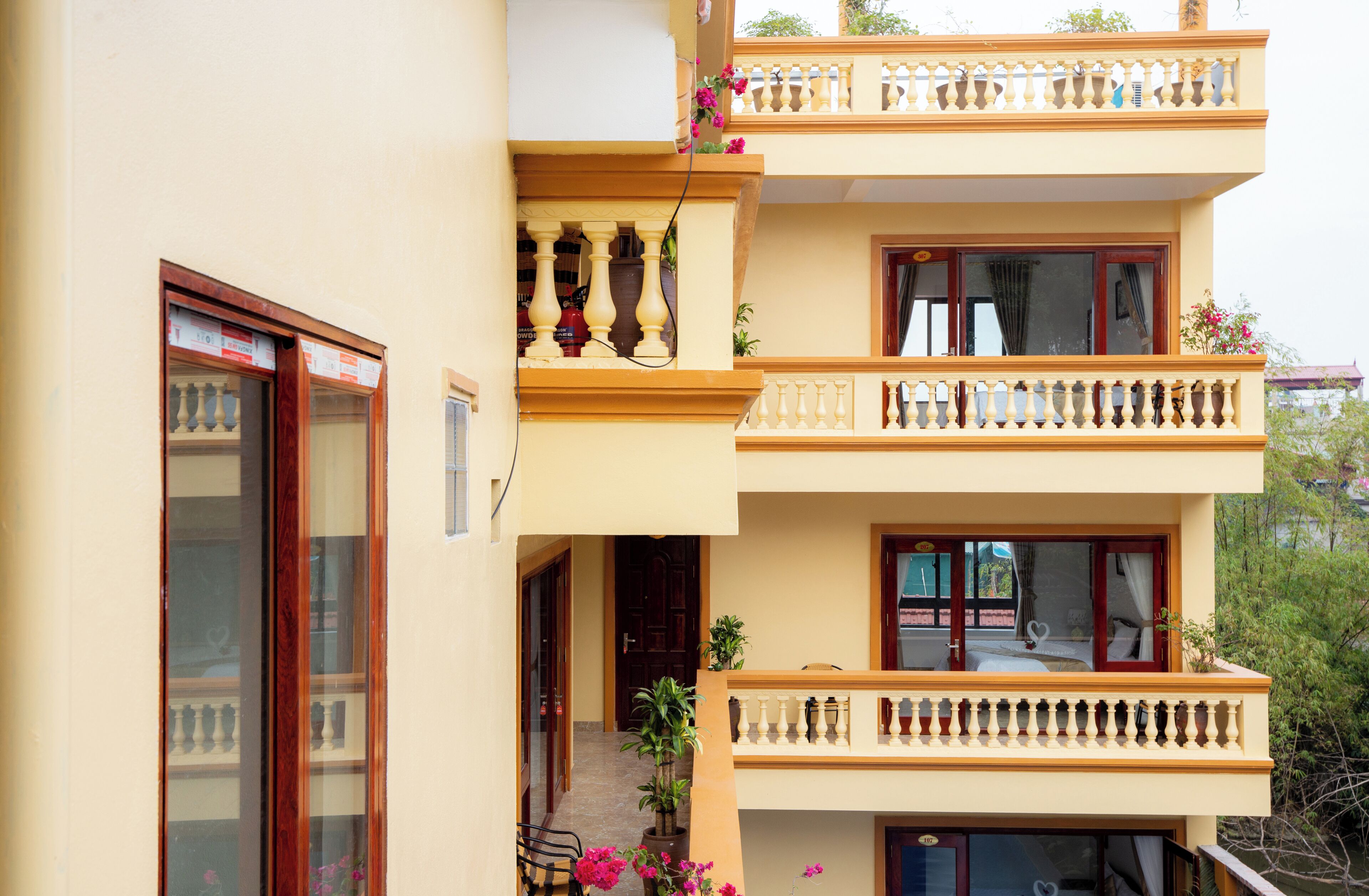 A multi-story building with balconies, large windows, and potted plants.