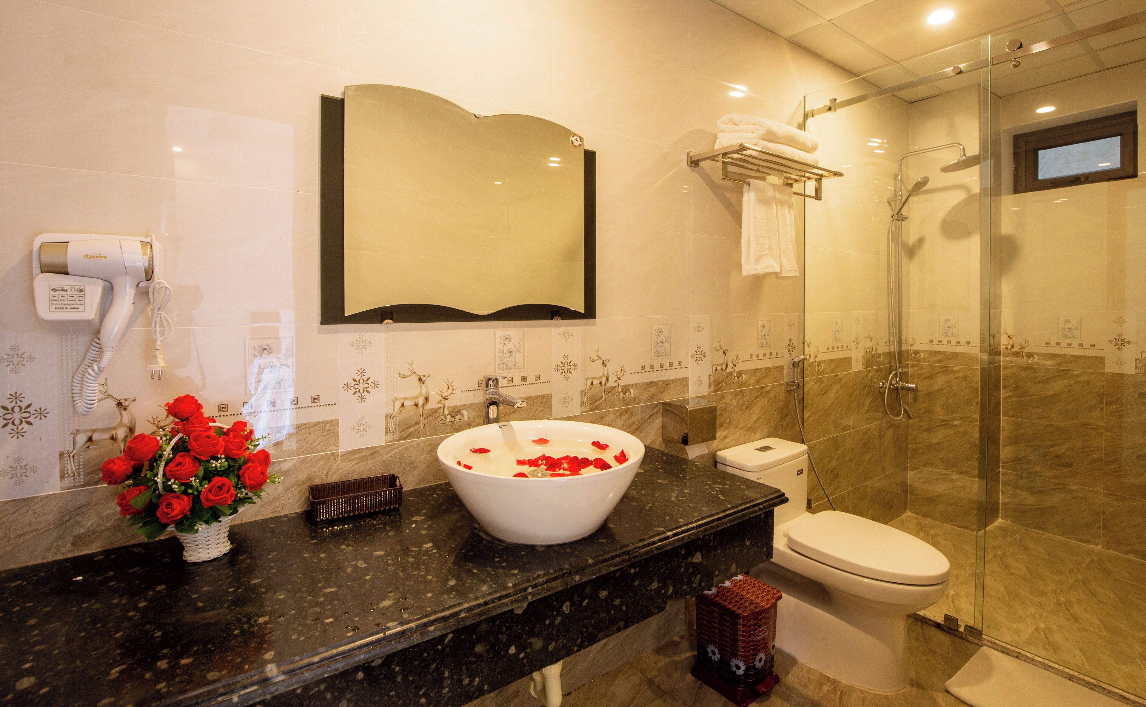 Een badkamer met een grote spiegel, een wastafel met een witte wasbak, een toilet en een douche.