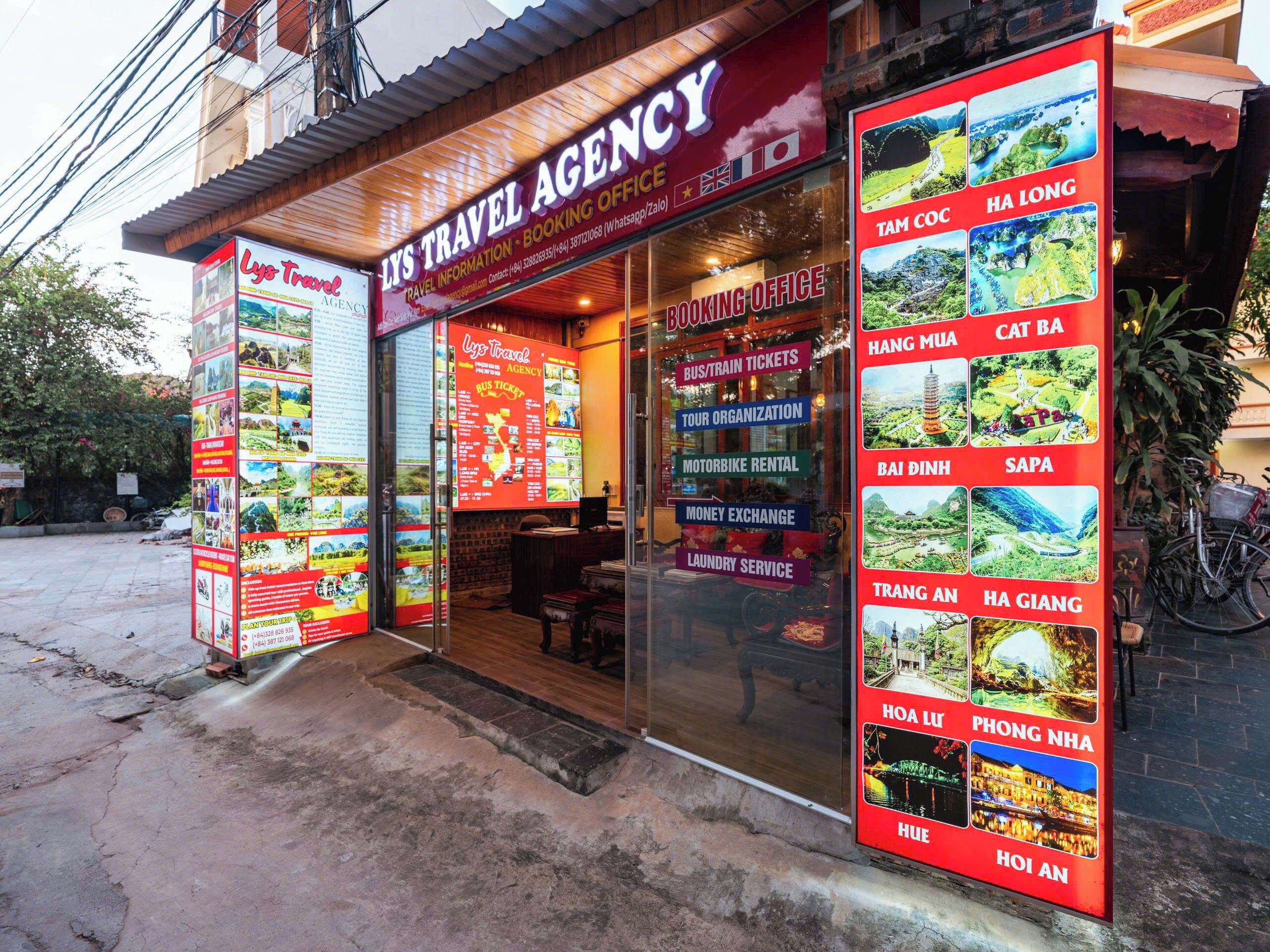 Une agence de voyages dont la façade est en bois et qui affiche de grandes affiches d’information.