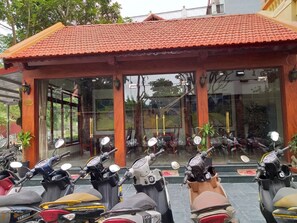 Un espace extérieur abrité avec plusieurs scooters garés devant.