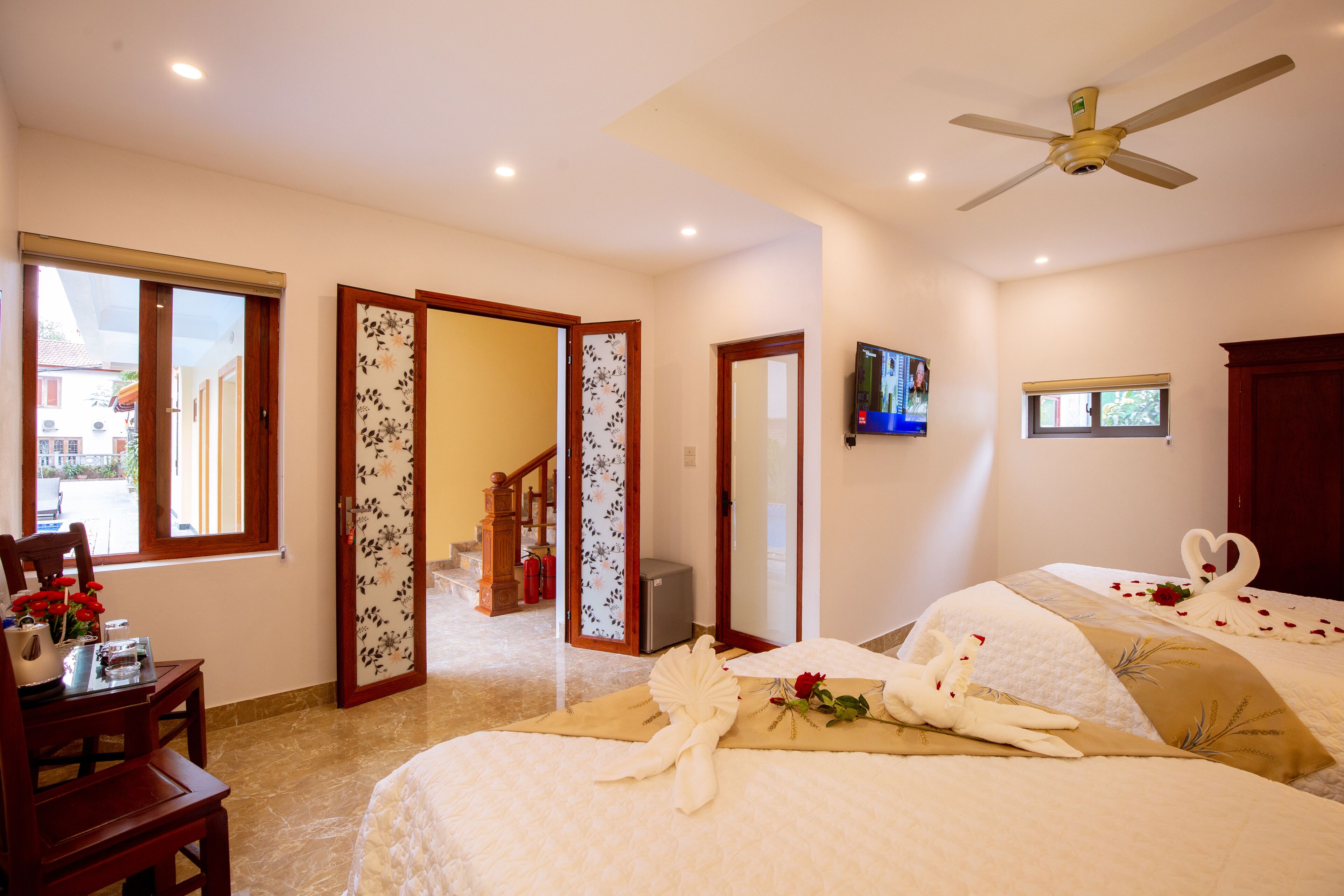 A hotel room with a bed, a desk, a chair, a TV, and a view of the outside.