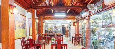 Un restaurante con vigas de madera en el techo, muebles de madera y vistas a bicicletas estacionadas afuera.