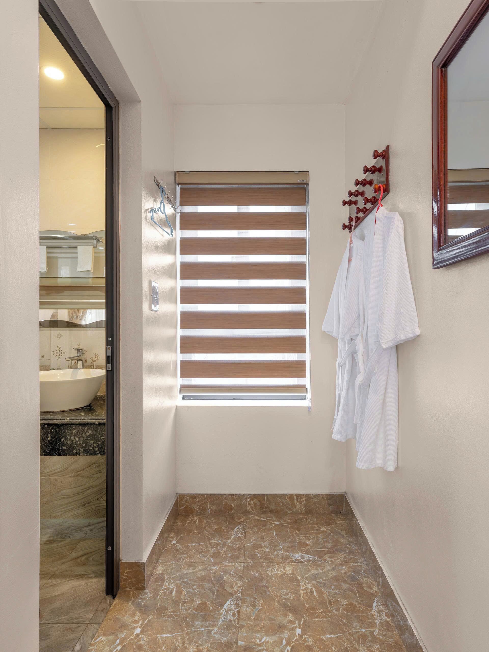 Un bagno con pavimento in marmo, un lavabo, una finestra con persiane e uno specchio.