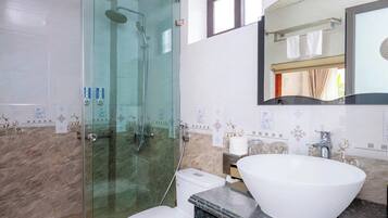 A modern bathroom with a glass-enclosed shower, a white toilet, and a large vessel sink.