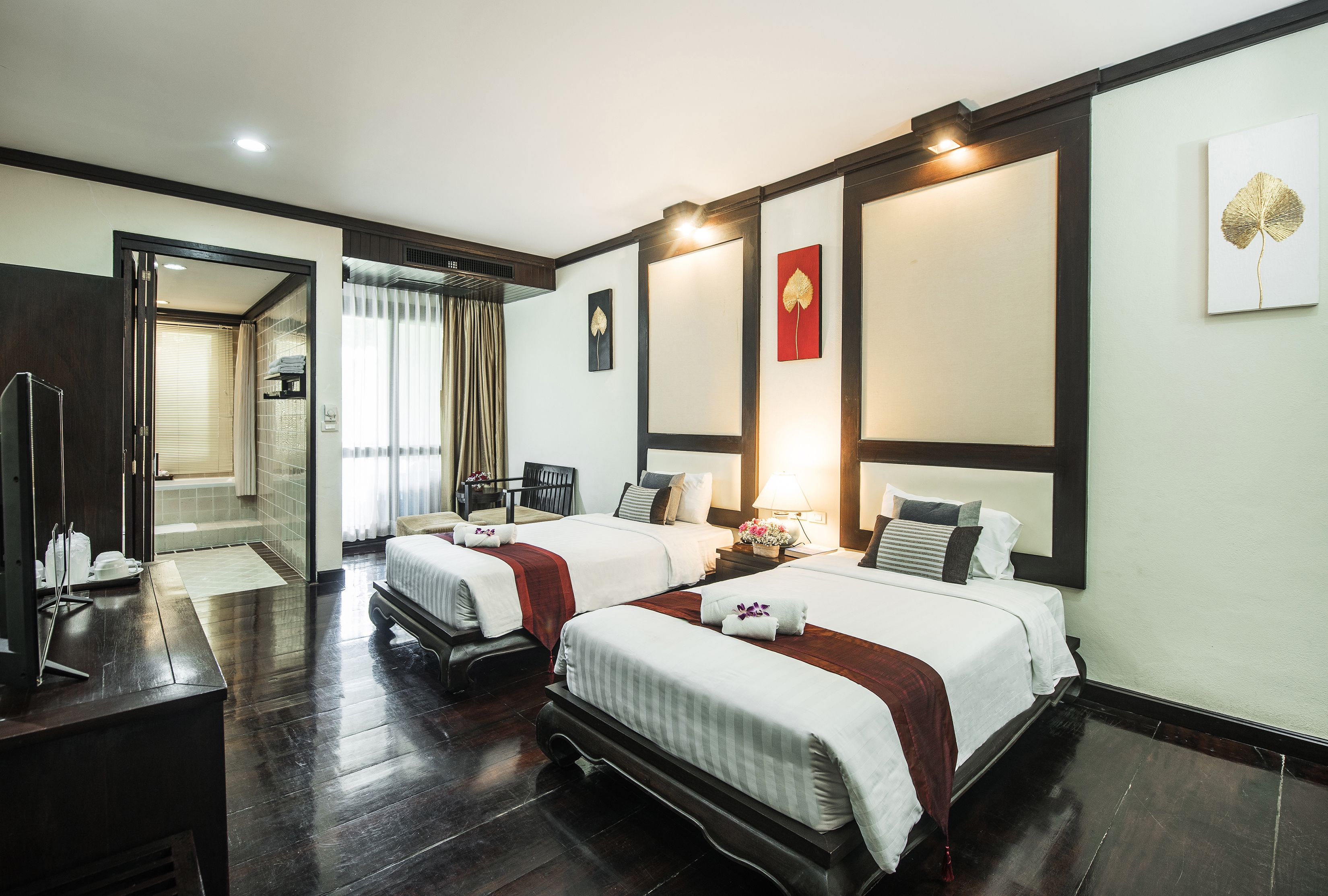 A hotel room with two beds, a desk, and a bathroom visible through an open door.