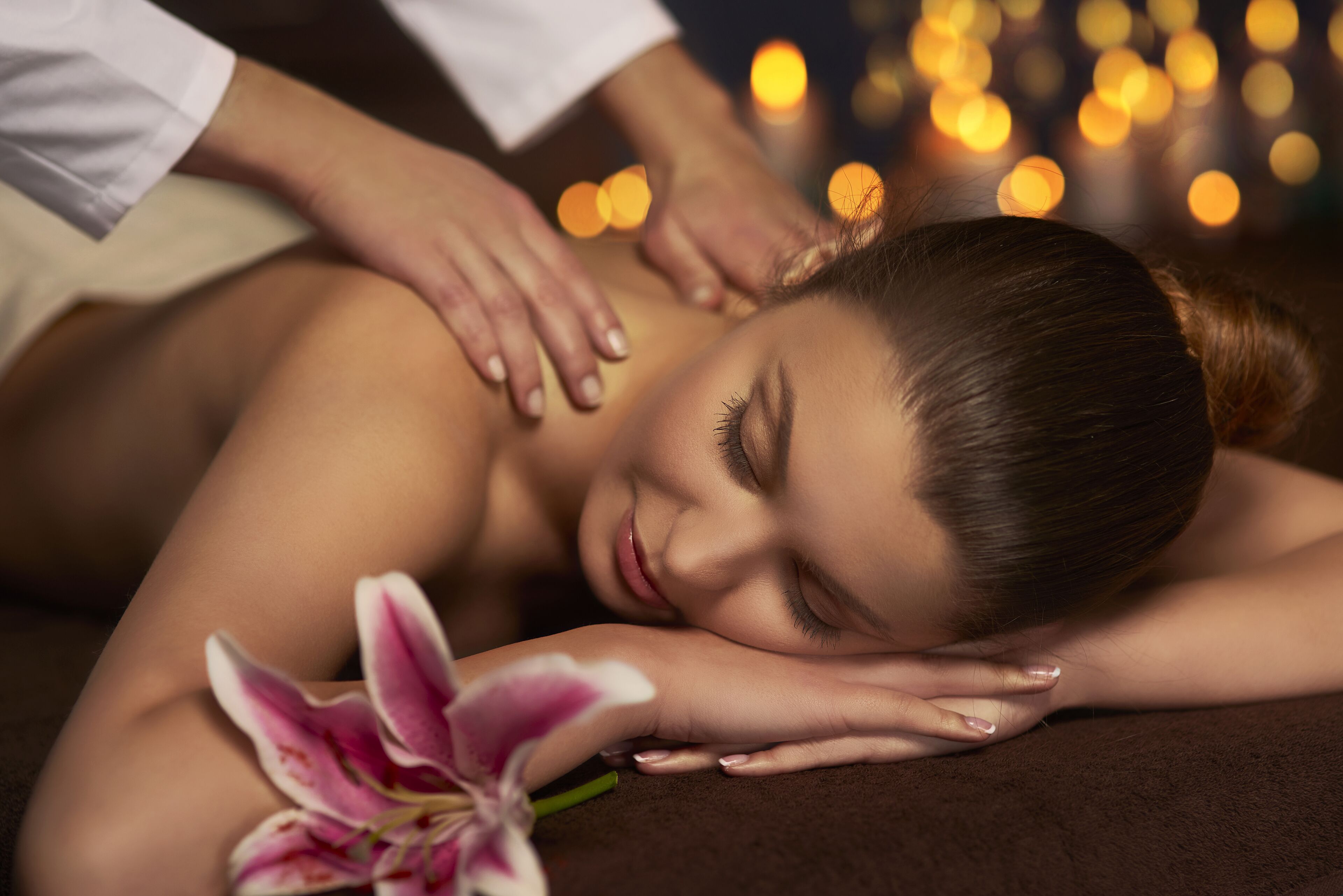 A person receiving a massage with a flower on the massage table.