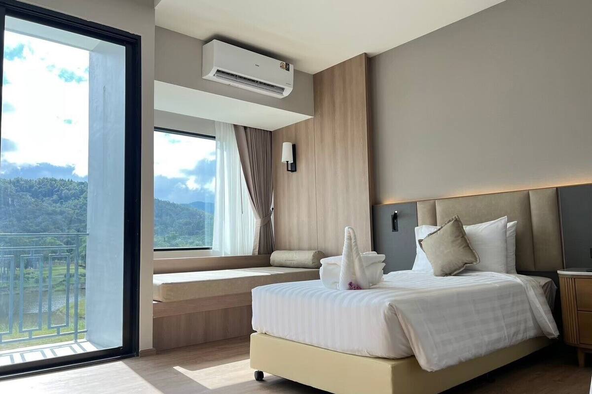 Ein modernes Schlafzimmer mit einem großen Bett und Blick ins Freie, inklusive Klimaanlage.