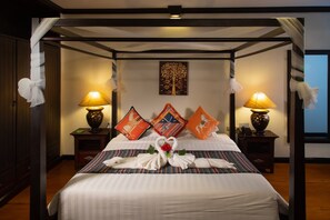 A four-poster bed with a heart-shaped centerpiece, two bedside lamps, and decorative pillows. - Gassan Khuntan Golf and Resort (Mae Tha)