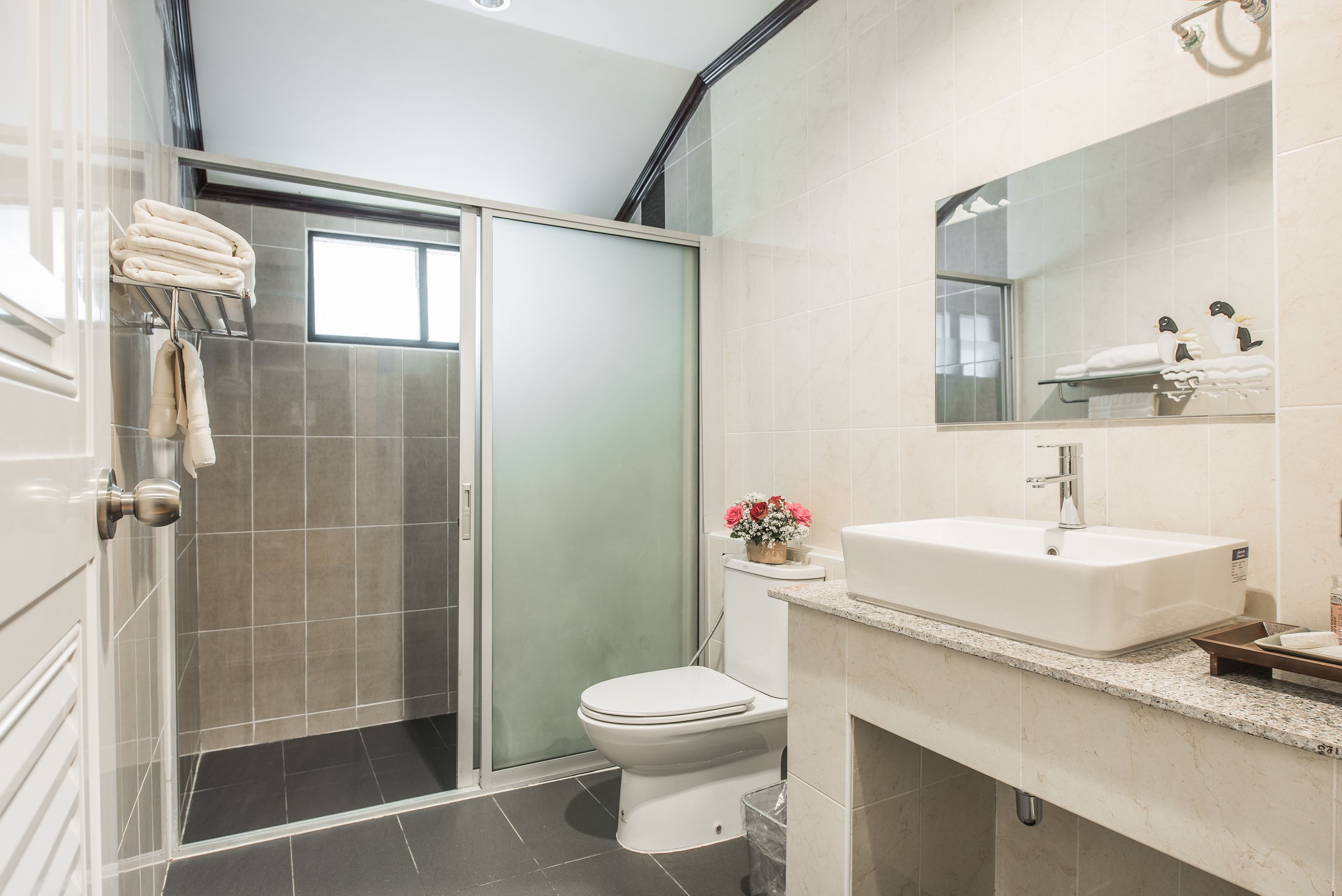 A modern bathroom with a glass shower enclosure, a white toilet, and a sink with a mirror above it.