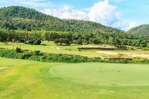 A golf course with well-manicured greens, sand bunkers, and a flagstick. - Gassan Khuntan Golf and Resort (Mae Tha)