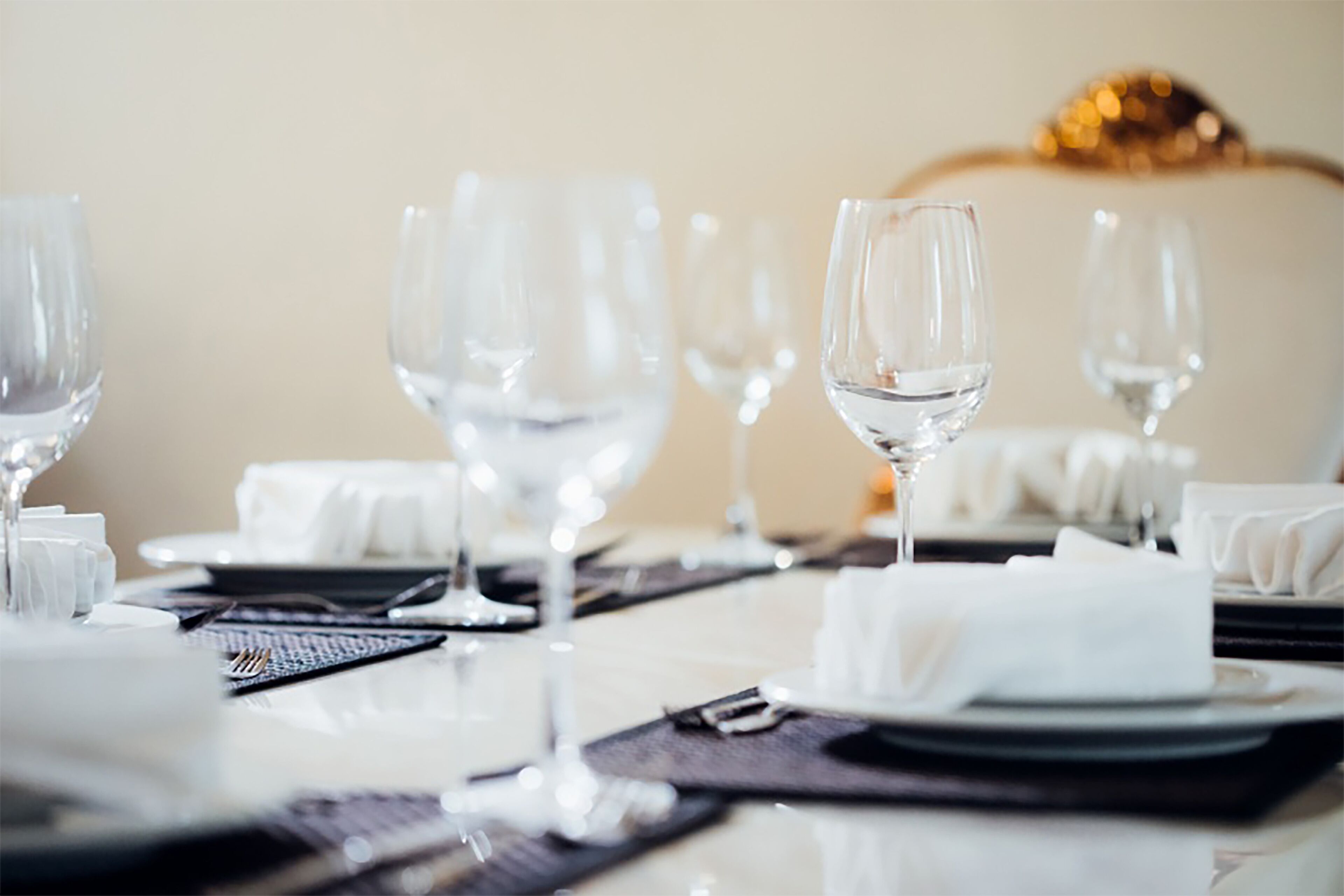 A dining table set with clear glassware, plates, and cutlery, with a white napkin and a decorative centerpiece.