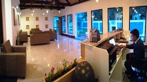 A modern hotel lobby with a reception desk, seating area, and large windows offering views of the outdoors. - The Kargil (Kargil)