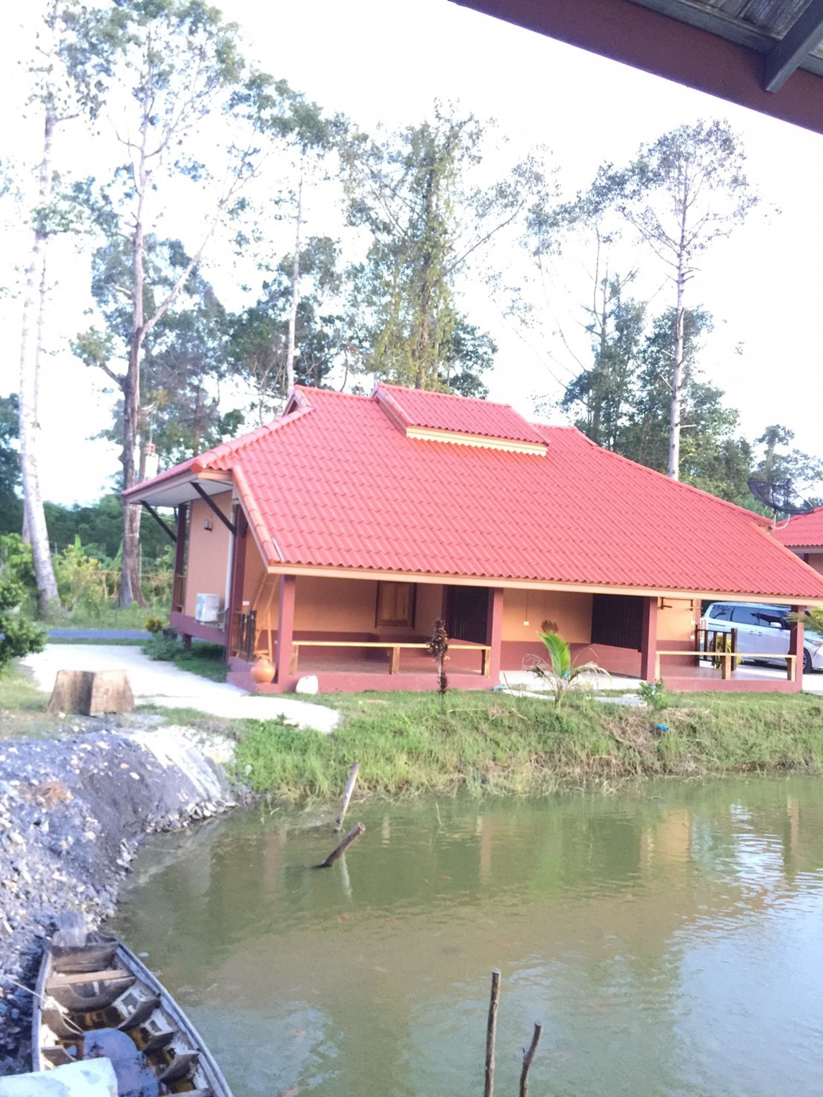 A building with a red roof, a porch, and a view of a body of water.