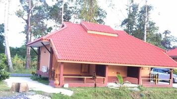 A building with a red roof, a porch, and a view of a body of water.