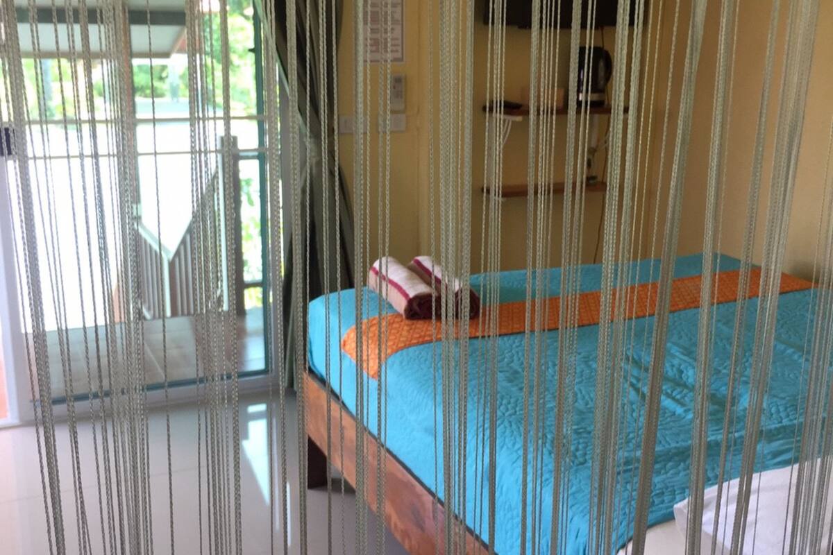 Ein Zimmer mit einem Bett, einem Fernseher und einem Fenster mit Vorhängen.