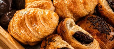 A wooden tray filled with various pastries, including croissants and chocolate-covered items.