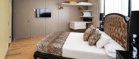 A modern bedroom with a bed, bedside tables, a TV, and built-in storage.