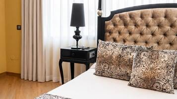 A hotel room with a large bed, a nightstand, a lamp, and sheer curtains.