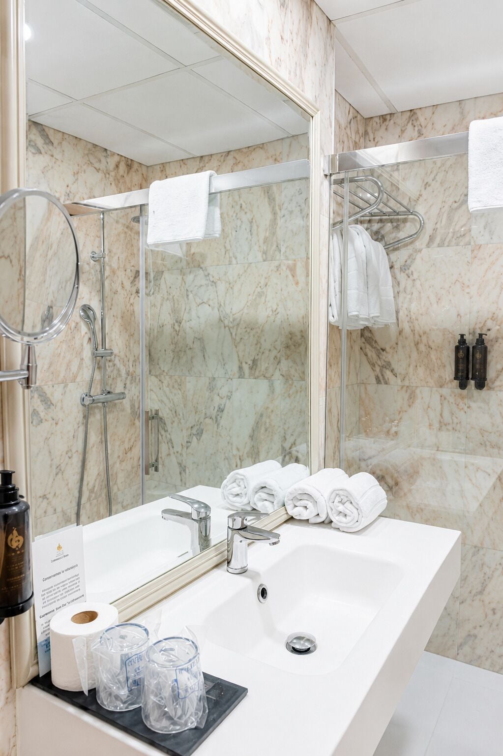 Une salle de bain avec un lavabo blanc, un miroir, une douche et un porte-serviettes.