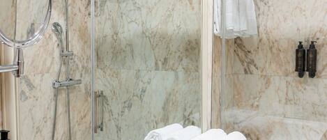 A bathroom with a white sink, a mirror, a shower, and a towel rack.