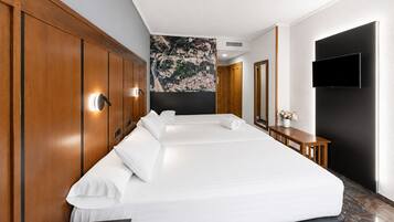 A hotel room with a large bed, wooden wardrobe, a flat-screen TV, and a wall-mounted artwork.