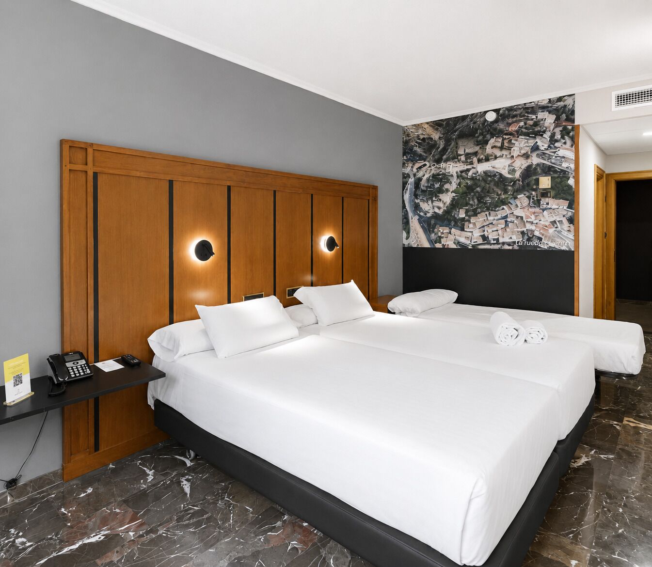 A hotel room with a large bed, two bedside tables, a phone, and a wall-mounted artwork.