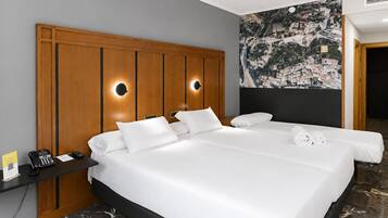 A hotel room with a large bed, two bedside tables, a phone, and a wall-mounted artwork.