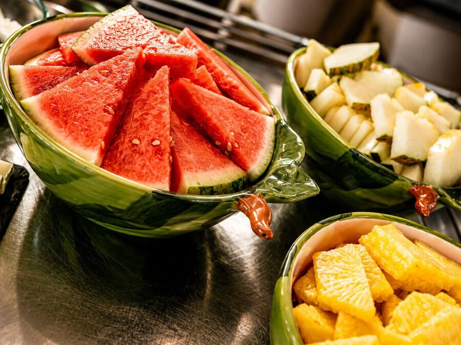 Una mesa con frutas variadas en cuencos, como sandía y piña.