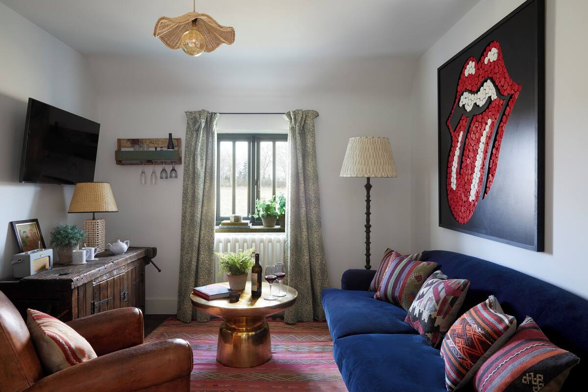 A living room with a blue sofa, a wooden cabinet, a television, and a large abstract painting.
