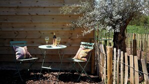 Une cabane en bois avec une petite table et deux chaises, une bouteille de vin et un verre de vin posés sur la table.