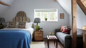 Une chambre confortable avec un lit, un canapé, une fenêtre donnant sur un beau paysage et une caisse en bois portant l’inscription « PRODUIT DE CEYLAN ».