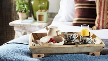 Ett frukostbricka med en skål med flingor, ett glas apelsinjuice och två koppar på ett träbricka.