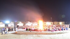 A nighttime outdoor gathering with tents and a central fire. - ADB Rooms Jaisalmer Dunes Camp (Jaisalmer)
