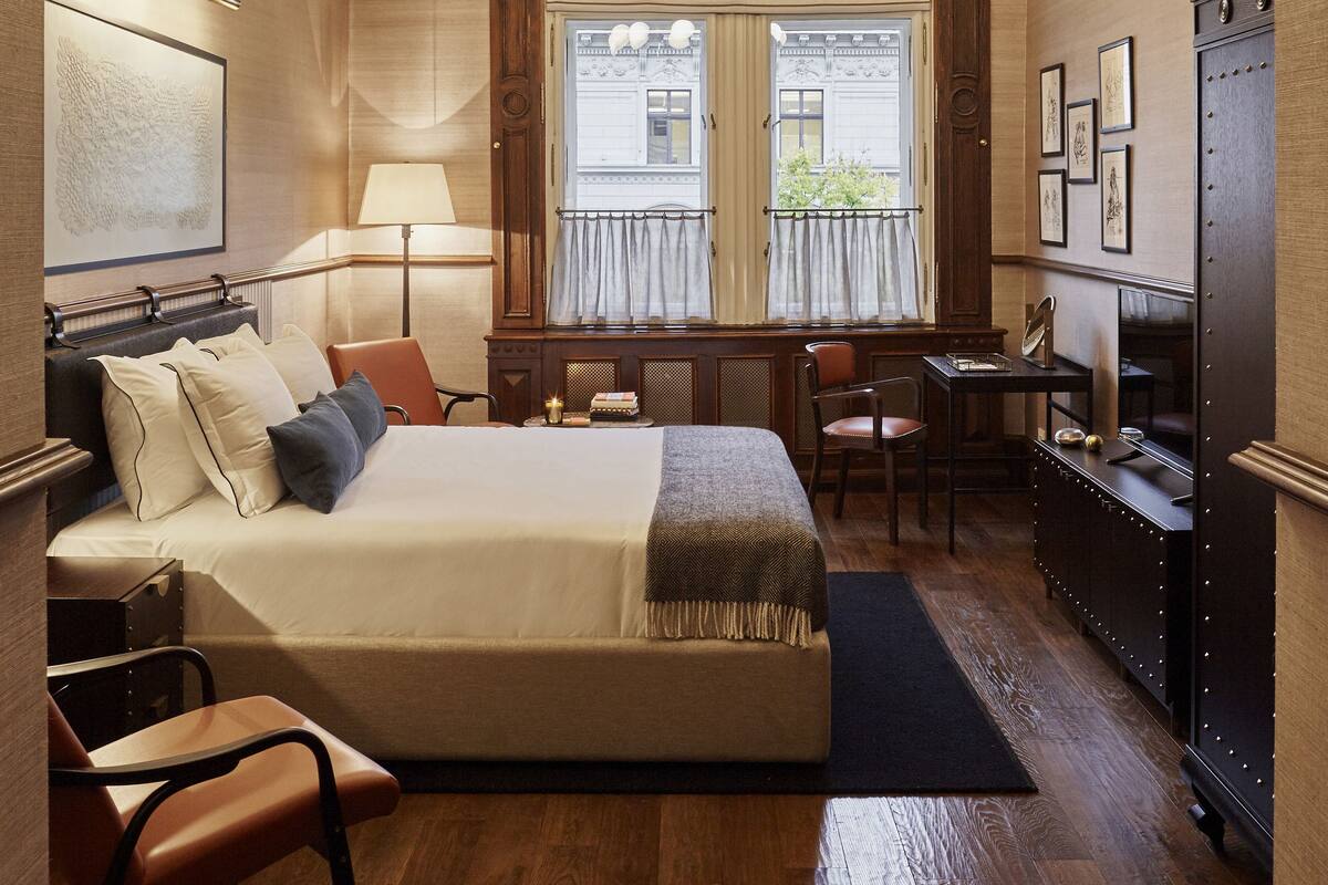 Una habitación de hotel con una cama grande, un escritorio, una silla, un armario y una ventana con cortinas.