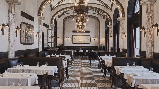A restaurant with a long, arched ceiling and chandeliers. Tables are set with white tablecloths and wine glasses. - Callas House (Budapest)