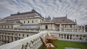 A rooftop terrace with a table and chairs, a view of a historic building with ornate architecture, and a clear sky. - Callas House (Budapest)